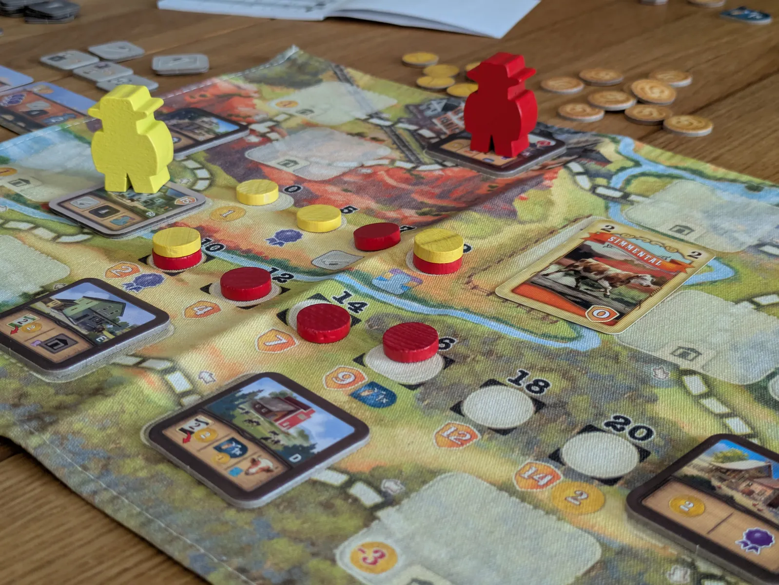 ボードゲーム「グレート ウエスタン トレイル エルパソ」の盤面。円形の道を進む牧場主コマと建物タイルの配置例